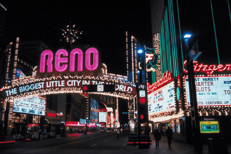 The Reno welcome sign surrounded by twinkling casino lights at night.