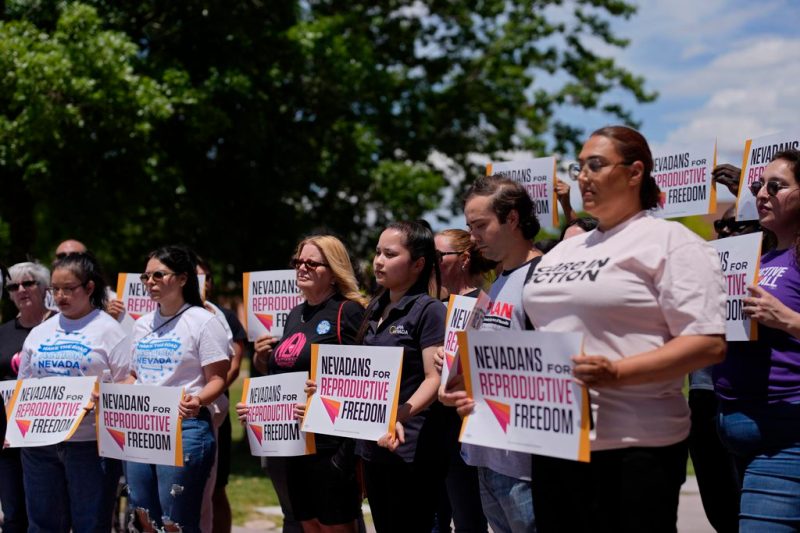 FILE - People hold signs during a news conference by Nevadans for Reproductive Freedom, Monday, May 20, 2024, in Las Vegas. At least four states will have abortion-related ballot questions in November's election and there's a push to get them before voters in several others. (AP Photo/John Locher, File)