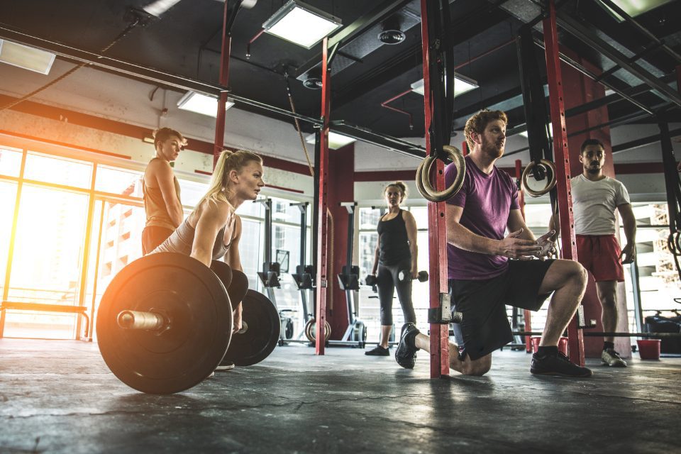 A woman deadlifting a heavy weight while a few men watch.
