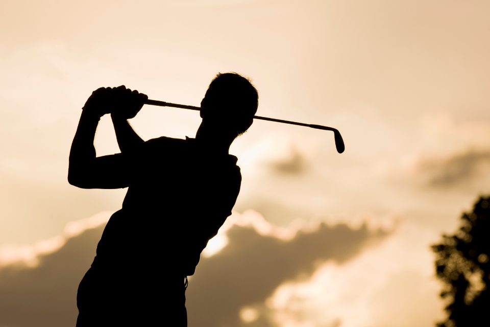 A silhouette of a golfer mid swing.