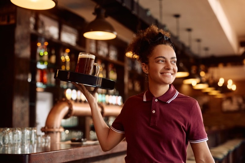 a woman carries a tray of drinks in a restaurant
