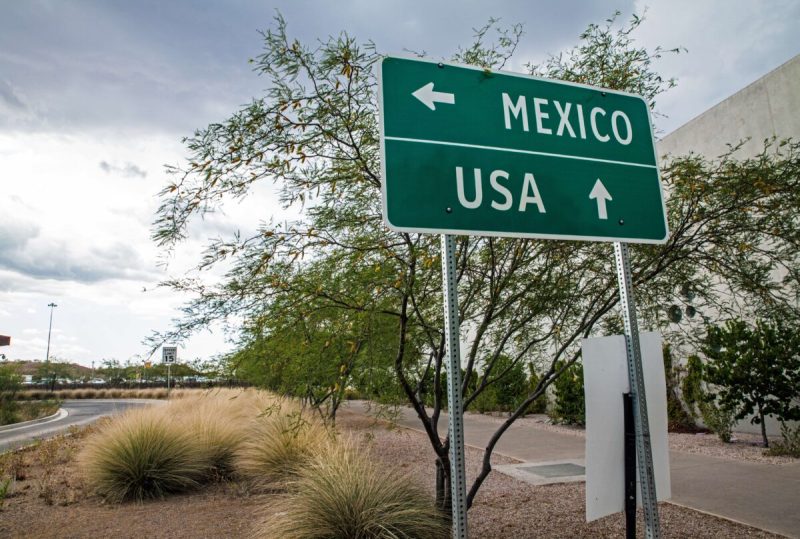 a green sign with white letters and arrows reading and directing folks to mexico and usa